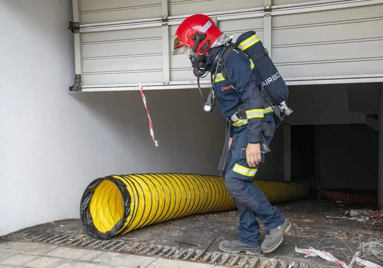 Bombero equipado en labores de mantenimiento en la ventilación de un garaje.