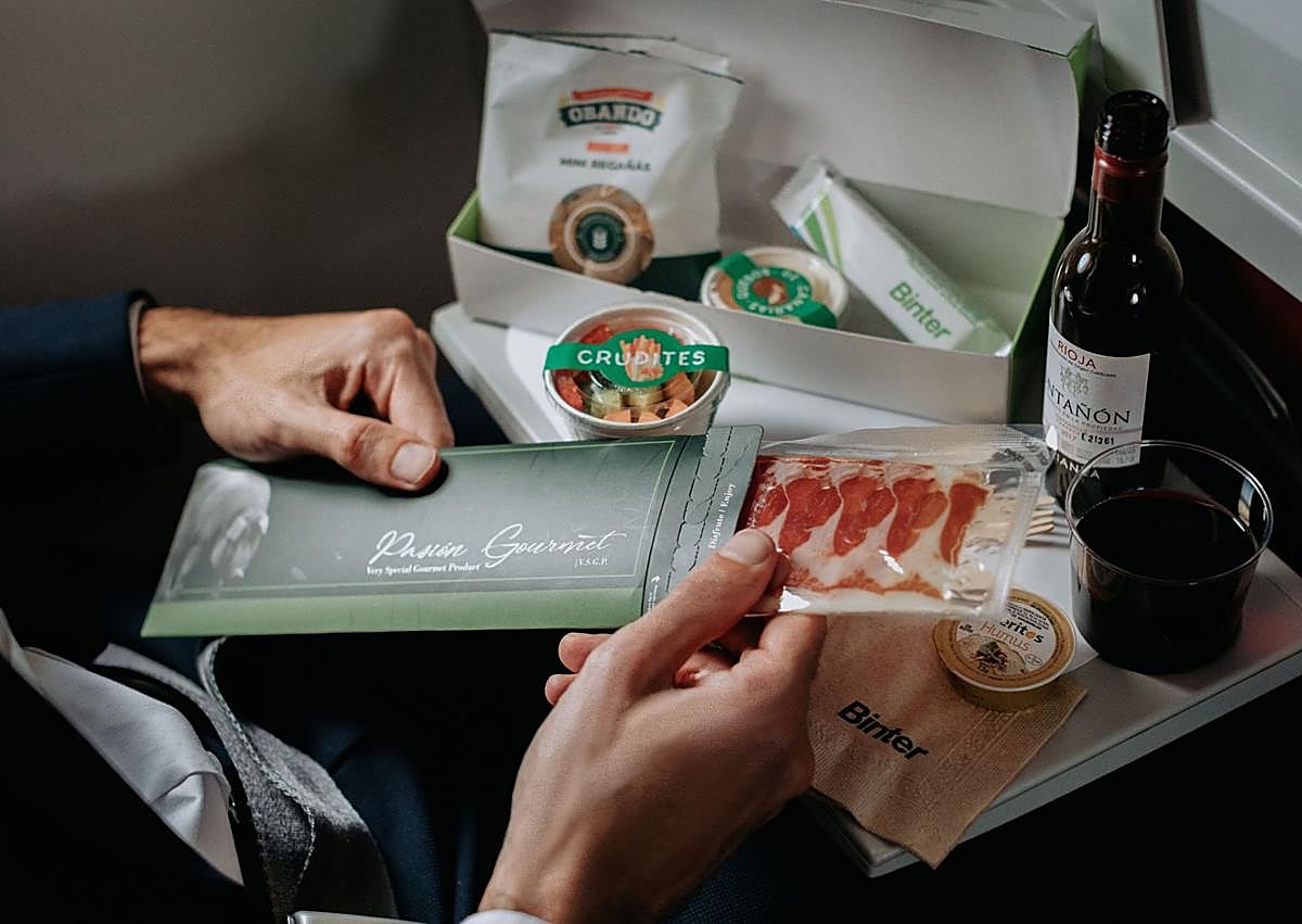 Imagen secundaria 1 - Un avión Embraer E195 E2 de Binter; menú a bordo de la aerolínea canaria; y una imagen de la inauguración de los vuelos directos entre Canarias y los aeropuertos de Pamplona. 