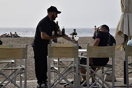 Un trabajador del sector turístico en un negocio en la playa de Las Canteras.