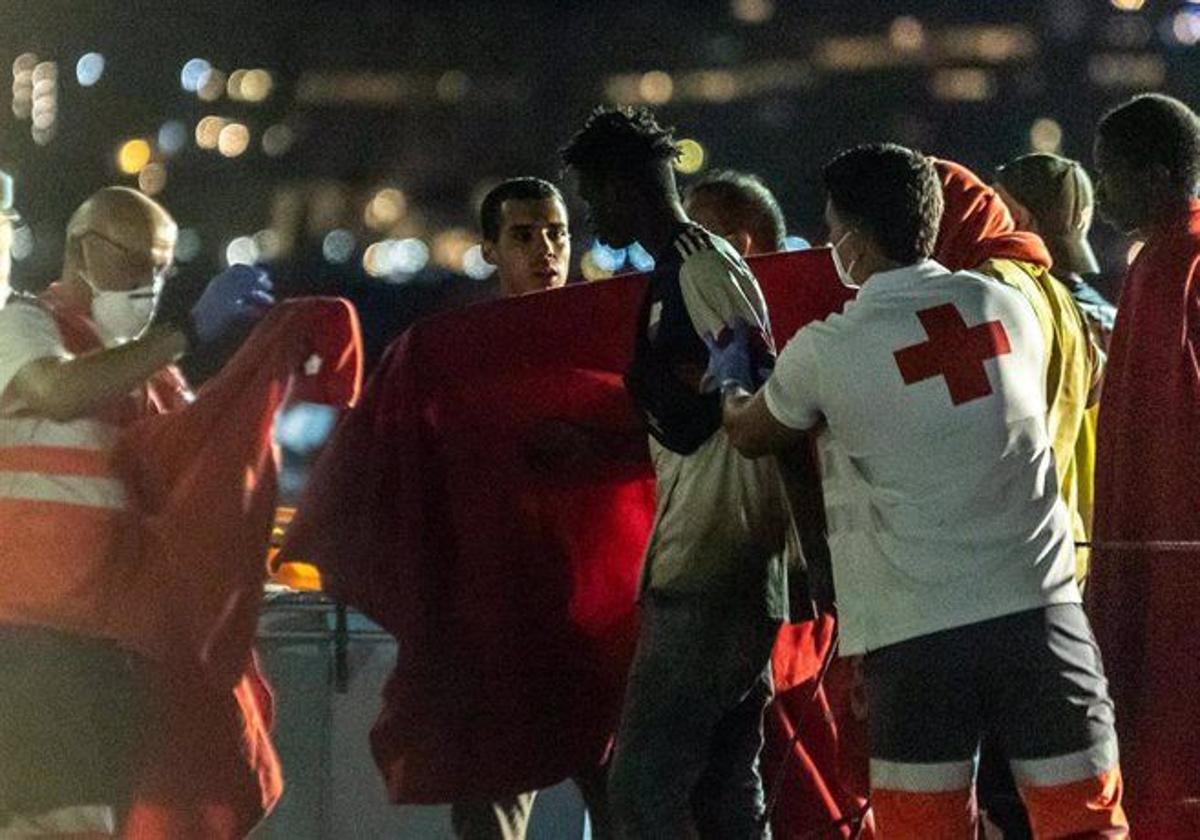 Trabajadores de la Cruz Roja reciben a las personas de un cayuco rescatadas por una embarcación de Salvamento Marítimo, en el muelle de Arguineguín.