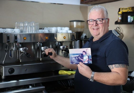 Luis Carlos Pérez, preparando un café, posa con una foto suya de hace más de 30 años en el mismo lugar.