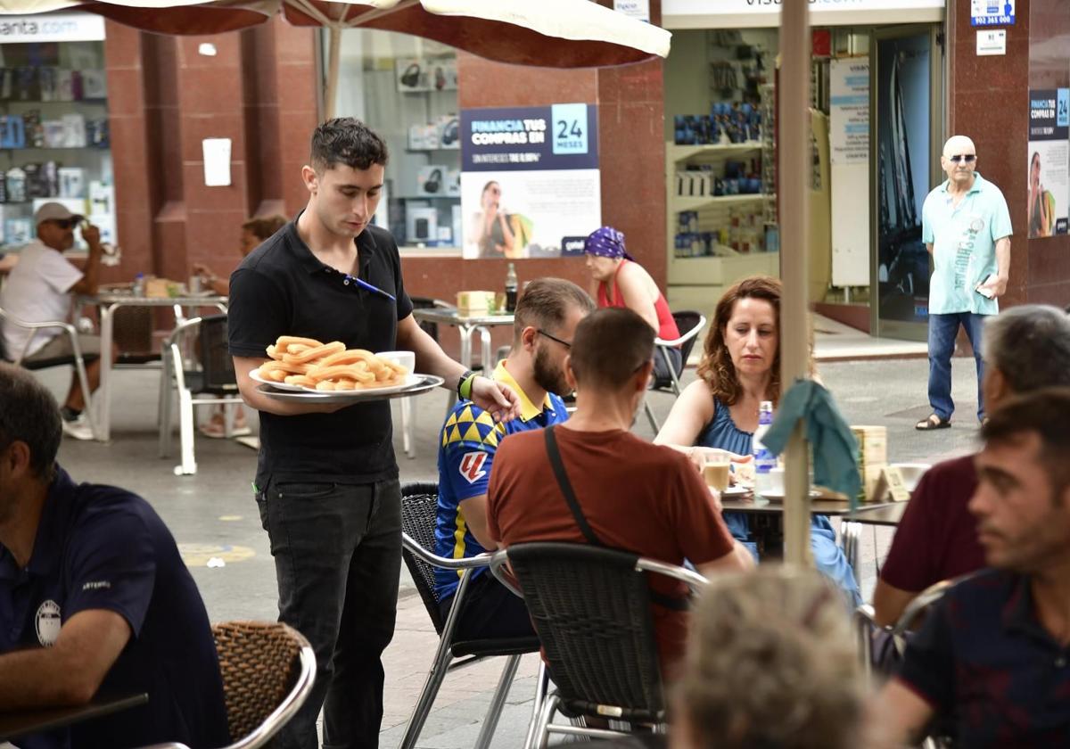 Un camarero atiende una terraza repleta de clientes.