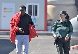 Imagen de un inmigrante junto a una guardia civil en La Restinga.