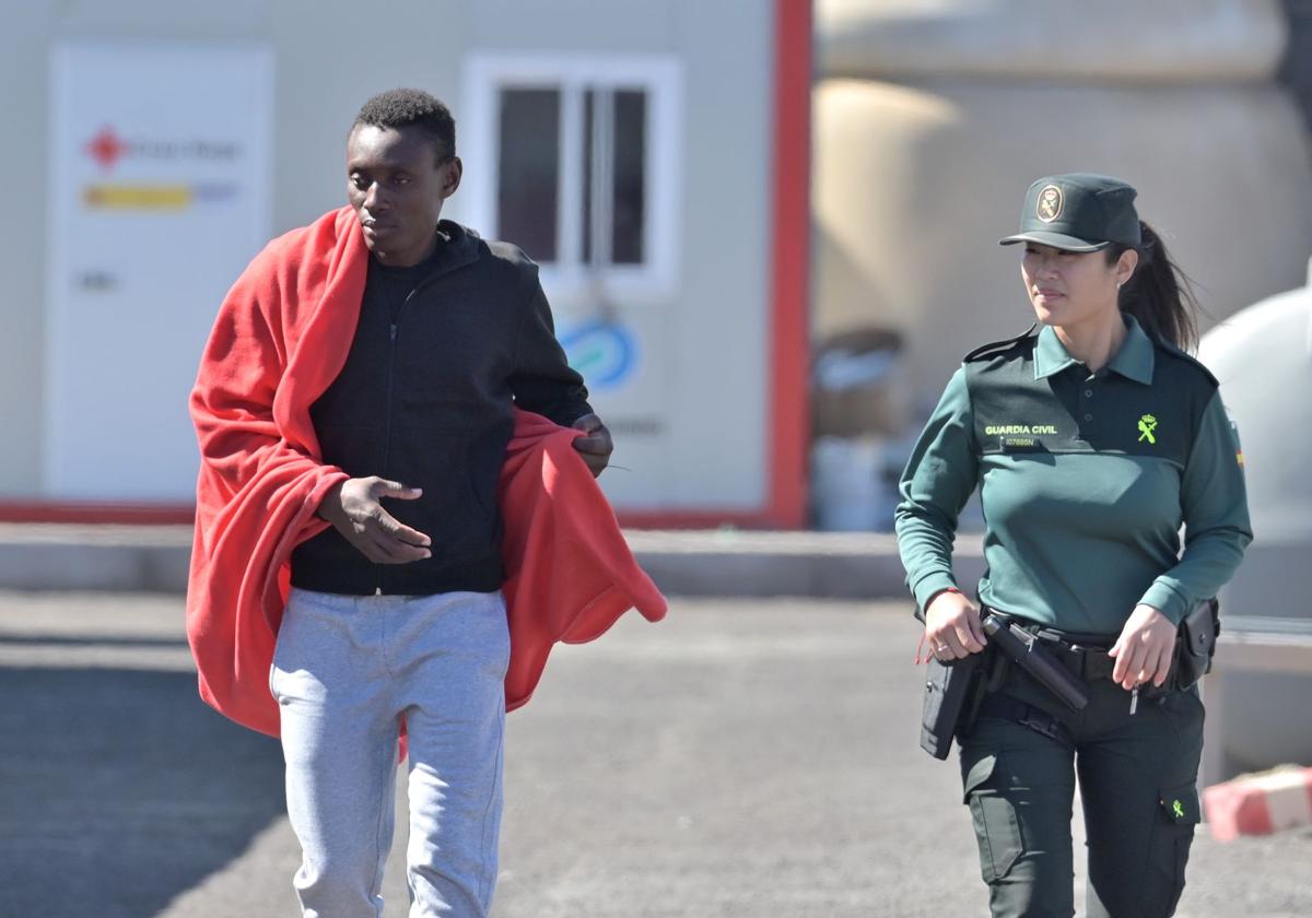 Imagen de un inmigrante junto a una guardia civil en La Restinga.