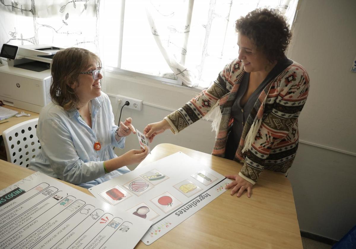 Amaya Marquina (izquierda) muestra a María del Mar Álvarez (derecha) los pictogramas seleccionados para usarlos en el taller de cocina.