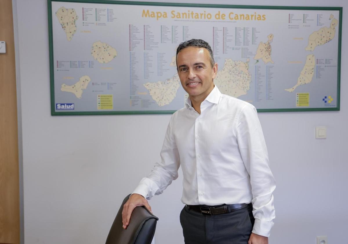 Carlos Díaz, en su despacho, junto a un mapa sanitario de Canarias.