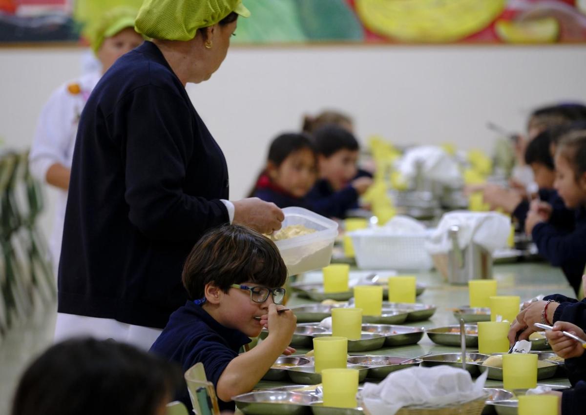 Imagen secundaria 1 - Una empleada del ecocomedor espolvorea con gofio el puré de los jóvenes comensales.