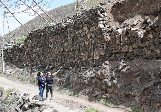 María y Carolina, junto al muro que da al único acceso a sus casas y registra desprendimientos.