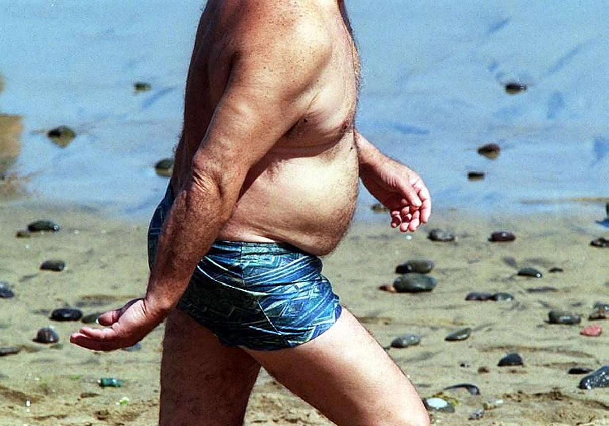 Imagen de un hombre con sobrepeso caminando por una playa canaria.