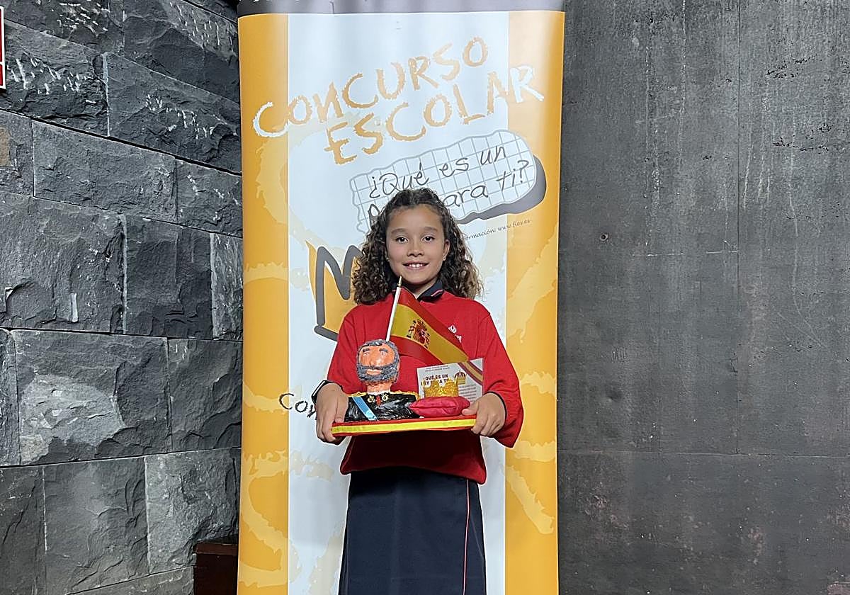 La joven estudiante posando con el busto dedicado al Felipe VI.