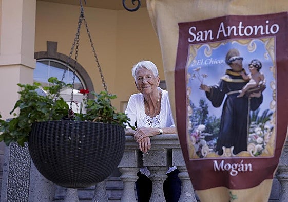 Natasha Betancor, apoyada en la balaustrada, se asoma junto al cartel que anuncia las fiestas.