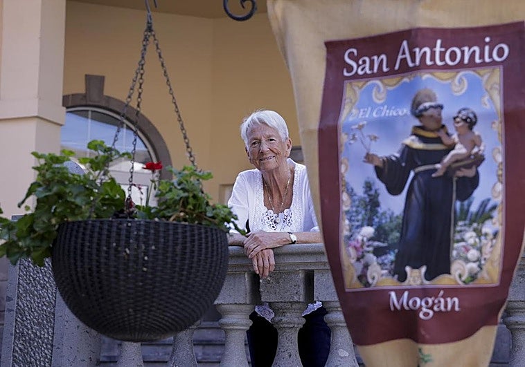 Natasha Betancor, apoyada en la balaustrada, se asoma junto al cartel que anuncia las fiestas.