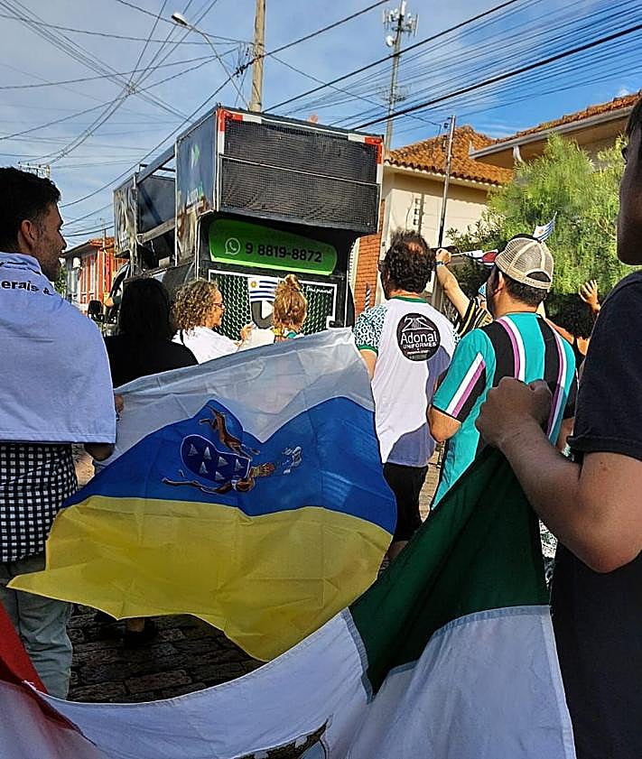 Imagen secundaria 2 - Imagen de las compañías participantes durante la fiesta del festival; una imagen de 'Salomón y La Discriminación Positiva'; y los integrantes de la compañía isleña con una bandera de Canarias durante el carrusel celebrado por esta cita teatral brasileña.