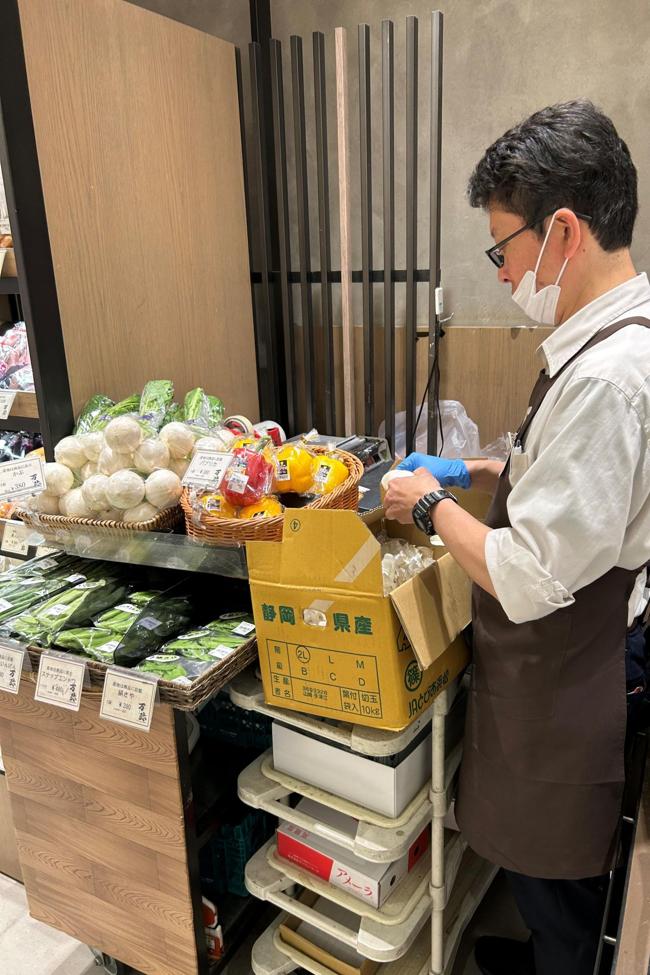 En el puesto de verduras un empleado preparando las cebollas para la venta