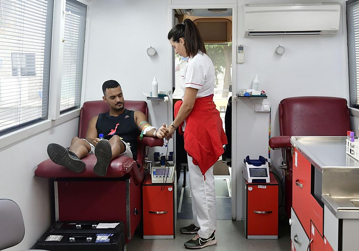 Un hombre dona sangre en una unidad móvil.