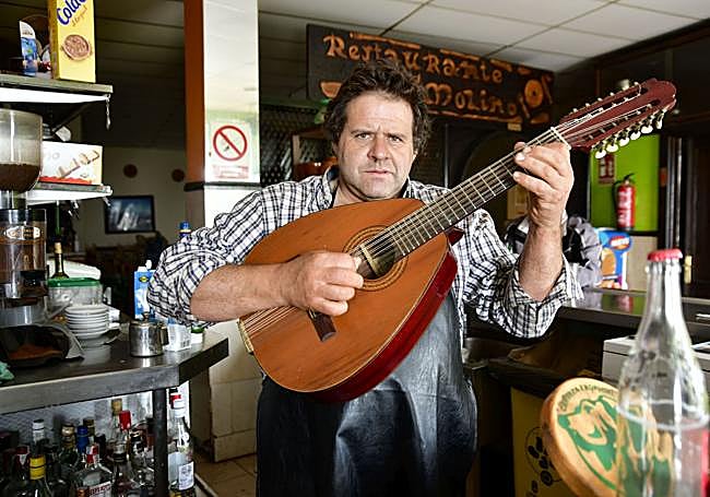 Francisco García tocando su bandurria en su bar restaurante El Molino.