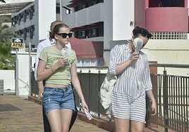 Dos mujeres combaten el calor con ventiladores de mano en el sur de Gran Canaria.