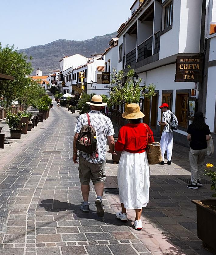 Imagen secundaria 2 - 1. Una pareja de visitantes en el mirador de la Plaza de Nuestra Señora del Socorro. 2. Un grupo de personas disfruta de la piscina municipal de Tejeda, con vistas al Roque Bentayga. 3. Una pareja de turistas camina de la mano por una de las principales calles de Tejeda.
