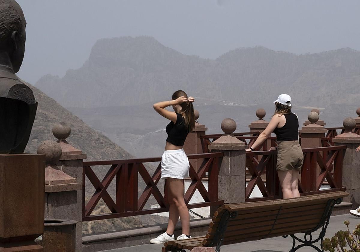 Imagen principal - 1. Una pareja de visitantes en el mirador de la Plaza de Nuestra Señora del Socorro. 2. Un grupo de personas disfruta de la piscina municipal de Tejeda, con vistas al Roque Bentayga. 3. Una pareja de turistas camina de la mano por una de las principales calles de Tejeda.