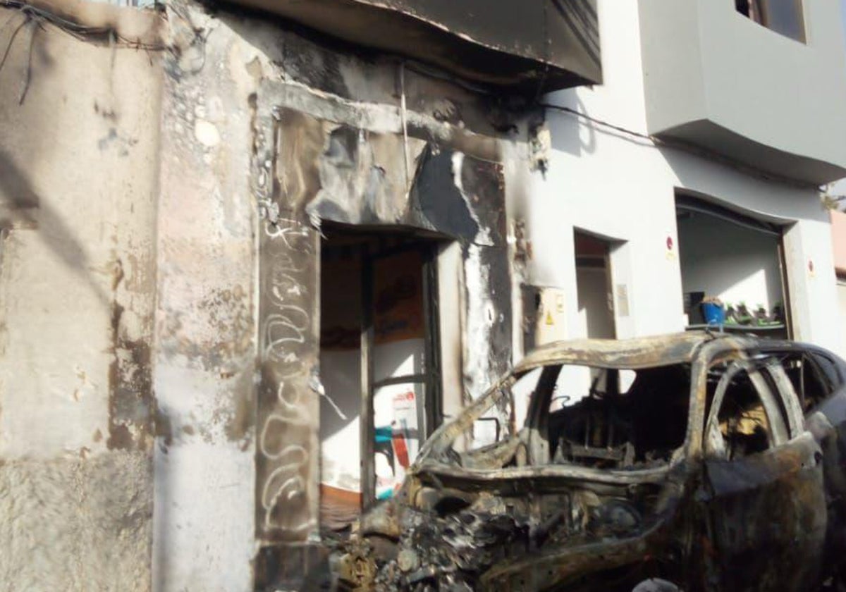 Imagen del coche y la fachada quemados.