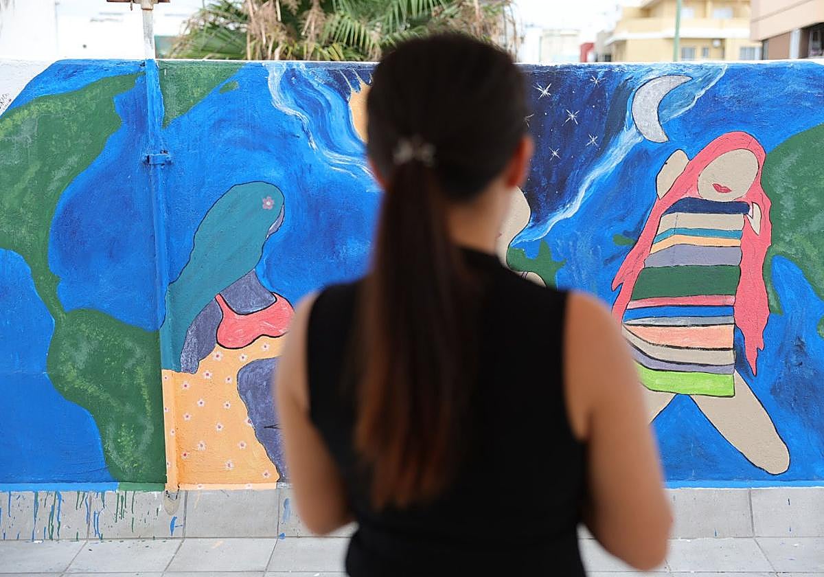 Martina, superviviente de la trata, frente a un mural pintado por mujeres atendidas en el Centro Lugo de Cáritas Diocesana de Canarias.