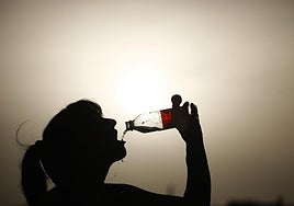 Una mujer bebe agua durante la ola de calor de agosto.