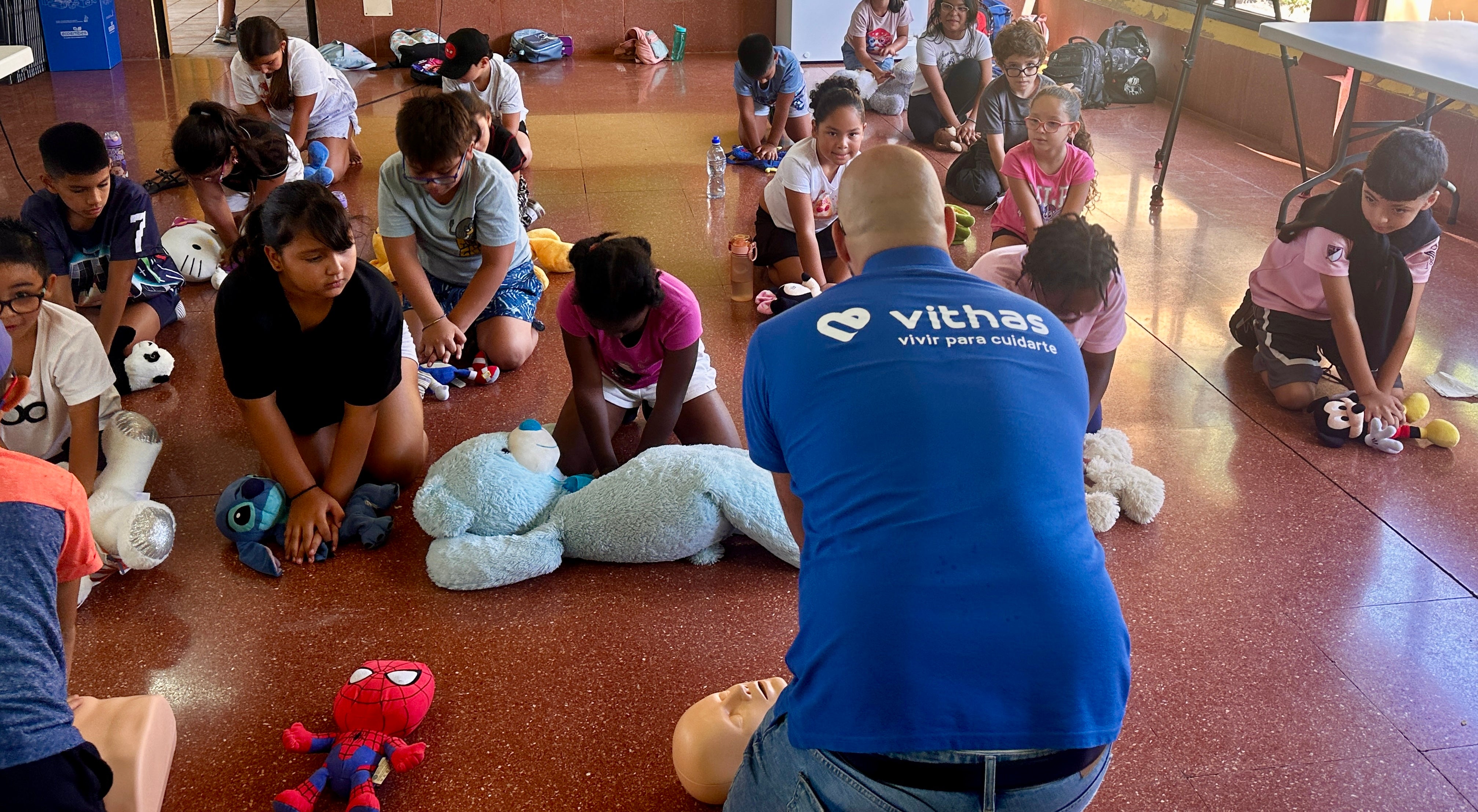 El director de enfermería de Vithas Canarias, Raico Pérez, les enseña a realizar la RCP con la ayuda de sus peluches.