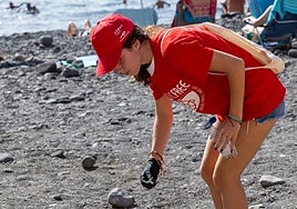 Una voluntaria recoge residuos en una playa.