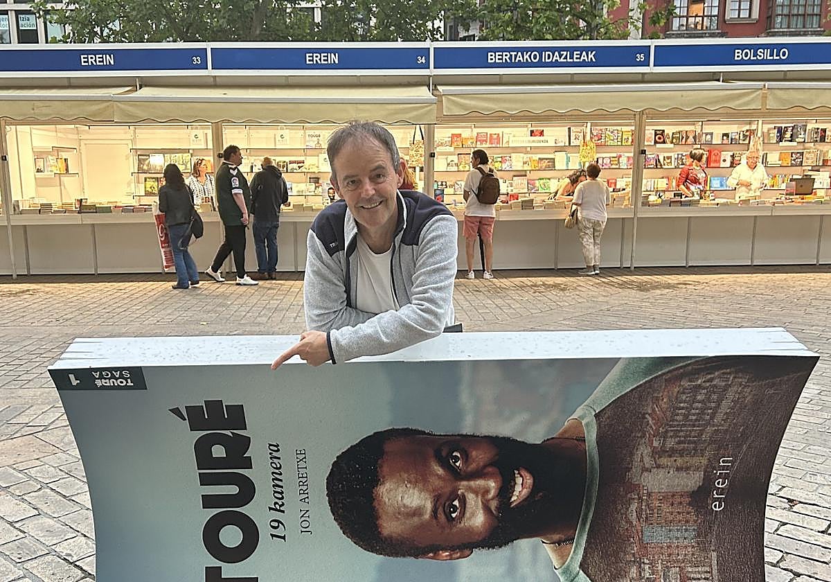 Jon Arretxe, junto a un cartel anunciador de Touré, el personaje que protagoniza su saga de novelas y que ha inspirado una serie de televisión.