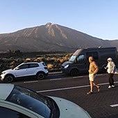 Un grupo de personas pasea junto a varios vehículos por el Parque Nacional del Teide.