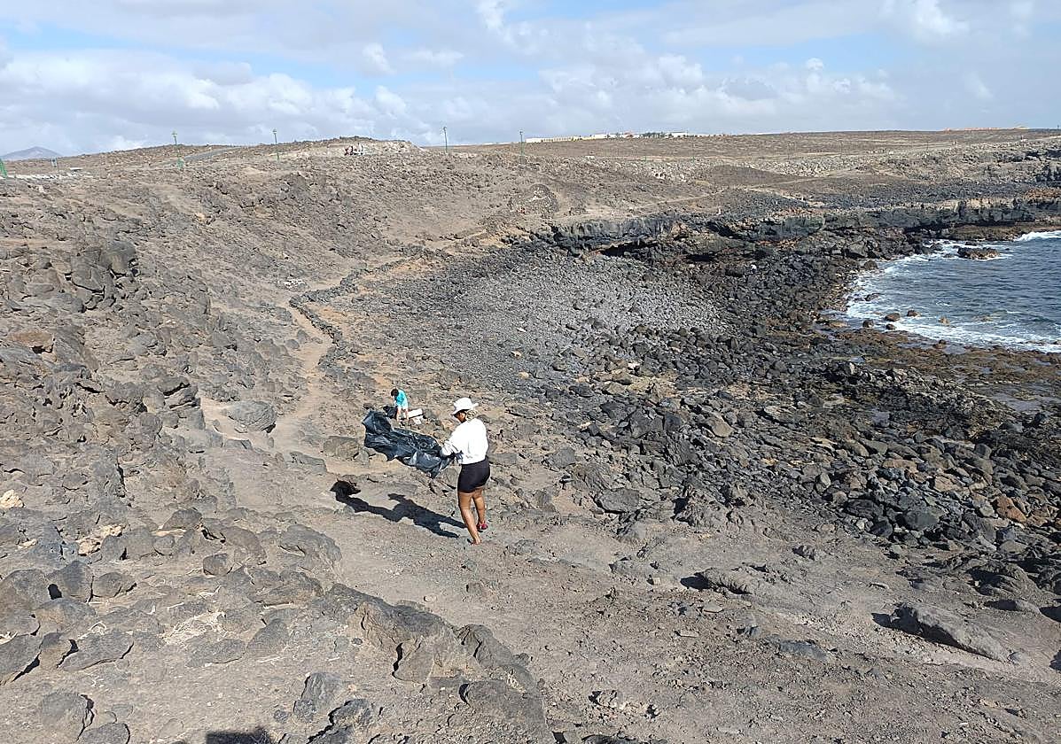 Dos voluntarias de Limpiaventura recogen recogen residuos en la costa del municipio de Antigua.