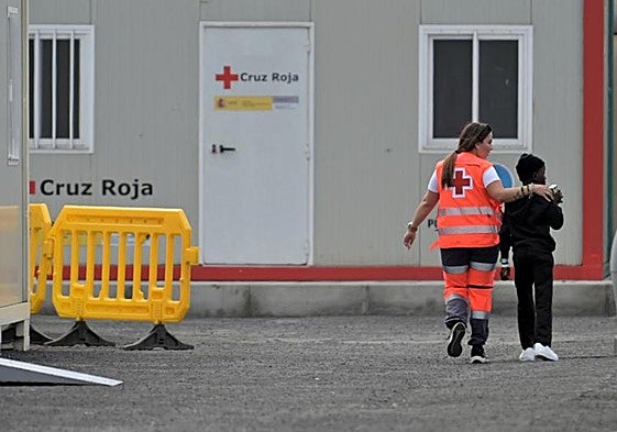 Un menor migrante junto a una trabajadora de Cruz Roja en el muelle de La Restinga.