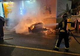 Un bombero apaga un contenedor incendiado.
