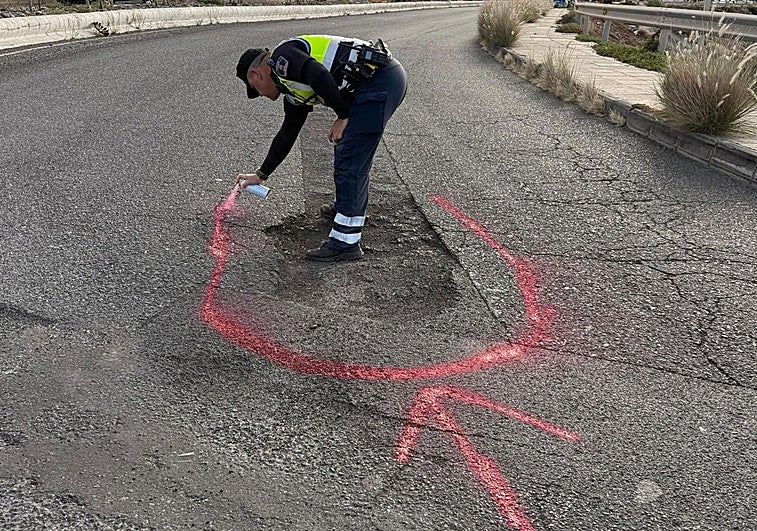 Agente señalizando con spray el bache revienta-gomas del vial costero en Telde.