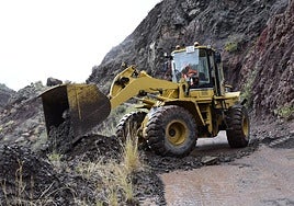 Un tractor despeja de tierra y piedras una carretera en el interior de la isla.