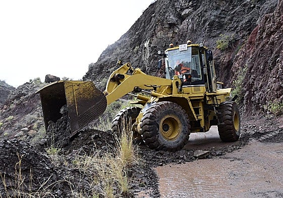 Un tractor despeja de tierra y piedras una carretera en el interior de la isla.