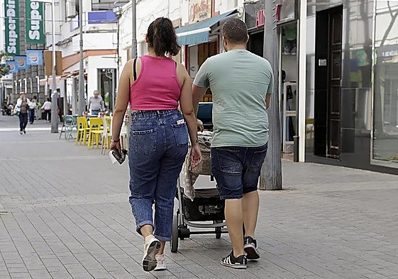 Pareja paseando con una criatura de corta edad.