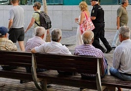 Imagen de archivo de varios hombres sentados en un banco.