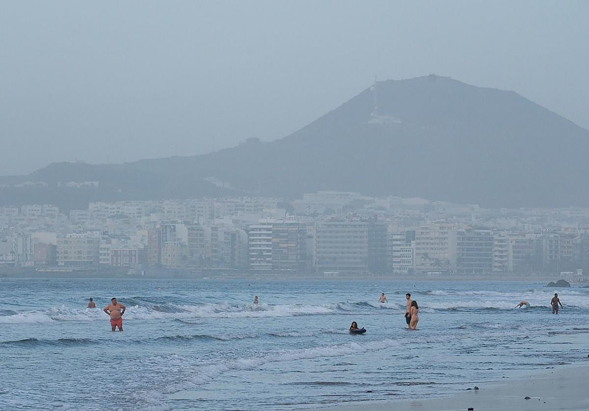 Las Canteras recibe a algunos bañistas en la tarde de este lunes, con la calima de fondo.