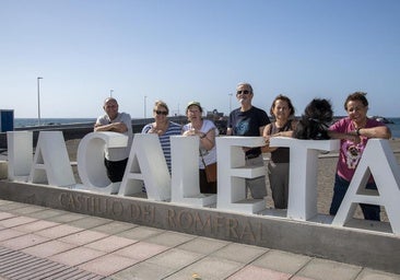 Parte del equipo de trabajo que colaboró en la publicación posa junto al nombre de la playa de Castillo del Romeral.