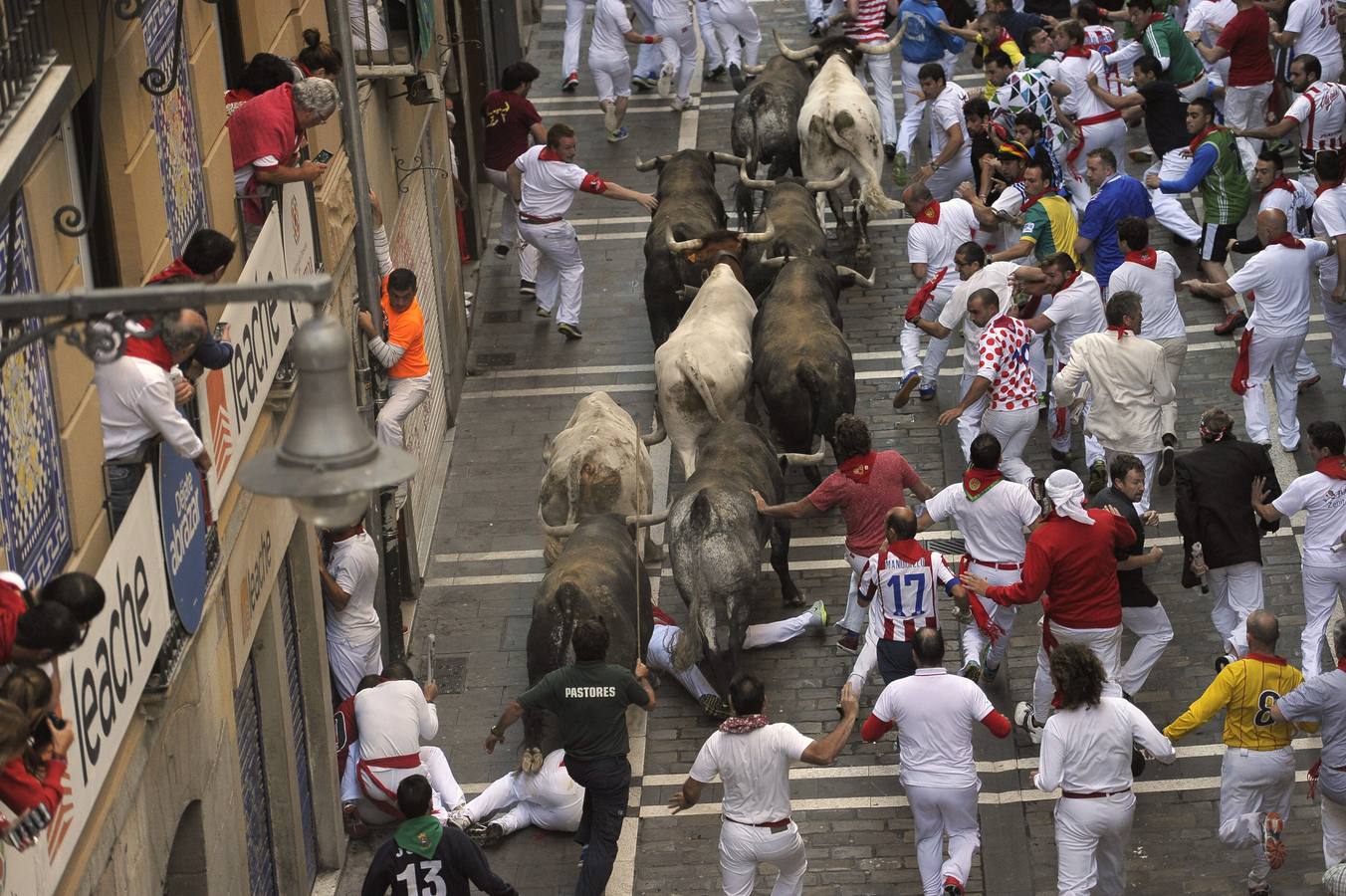 Un hombre intenta huir de los toros escalando por una tubería.