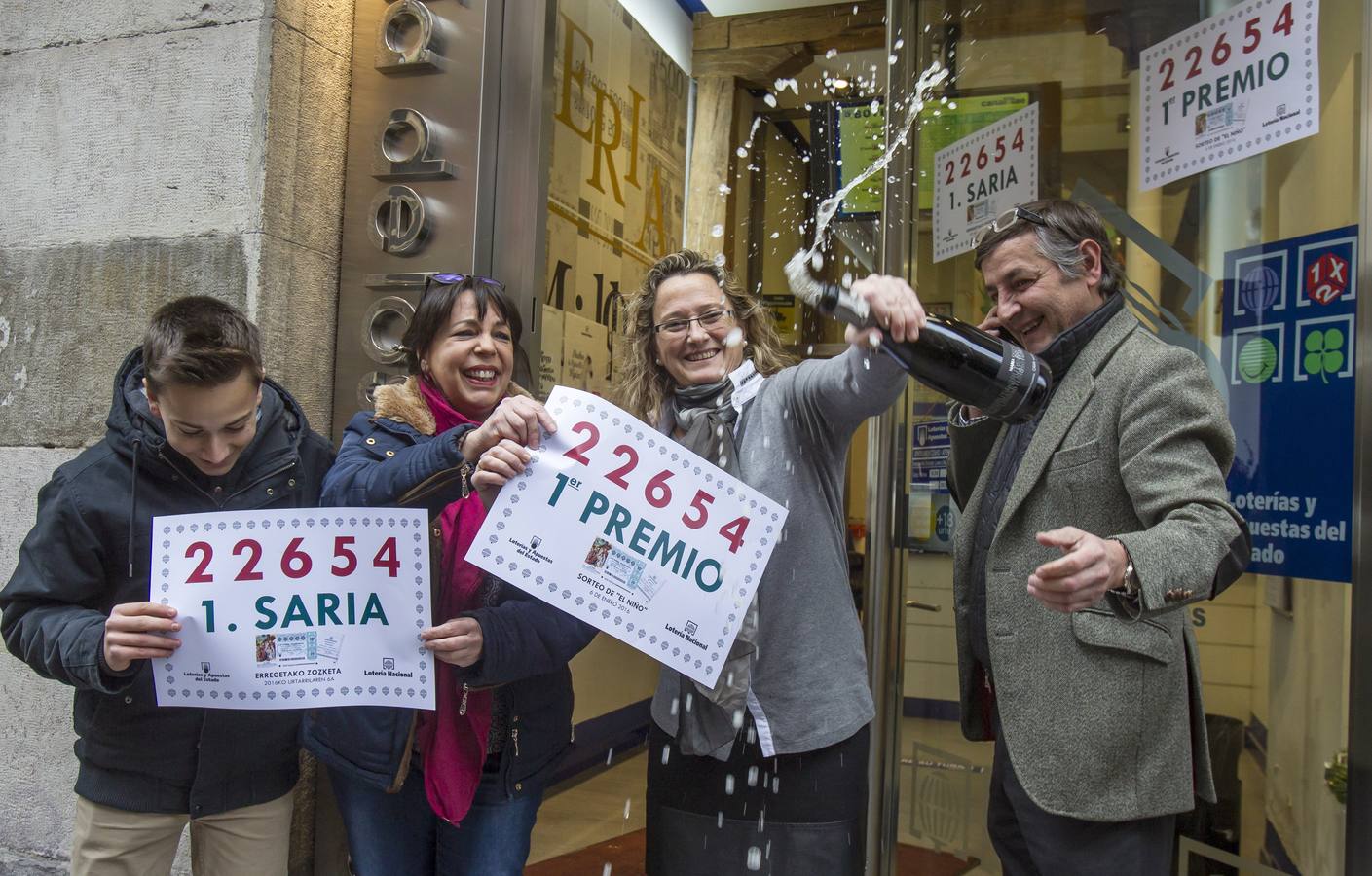 El titular de la administración número 25 de Bilbao "Lotería los 400 millones", Iñigo Gómez Barrengoa (d) y su familia, celebran los décimos del primer premio.