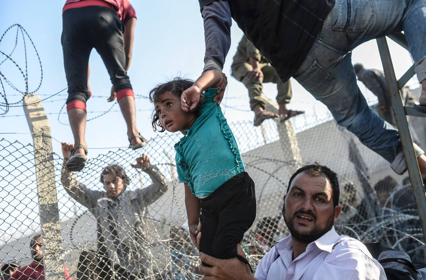 Tercer premio en la categoría de noticias. Imagen del fotógrafo de AFP Bulen Kilic que muestra la entrada de refugiados sirios por la frontera de Turquía.