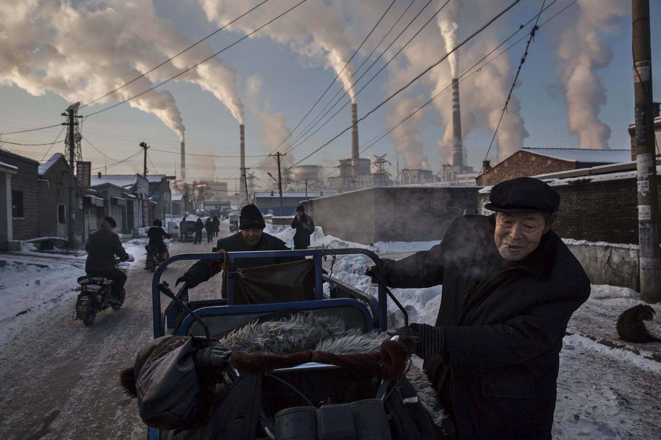 Primer premio en la categoría 'Vida diaria'. La imagen muestra a un hombre tirando de una especia de triciclo en una zona cercana a una planta alimentada por carbón en Shanxi, China