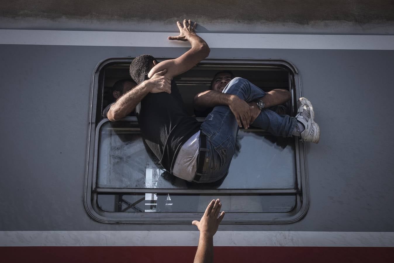 Foto de la serie ganadora de la categoría de noticias. La fotografía muestra a un inmigrante luchando por subir a un tren, en Zagreb (Croacia).