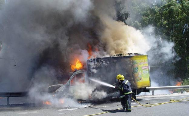 Bomberos actúan en un vehículo incendiado.