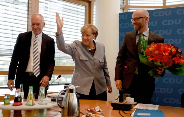 Merkel, ayer flanqueada por el secretario general de la CDU, Peter Tauber (dcha.), y el gerente de la formación, Klaus Schueler. :: O. A. / AFP