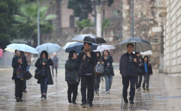 Turistas asiáticos, ayer de paseo por la capital bajo la lluvia.