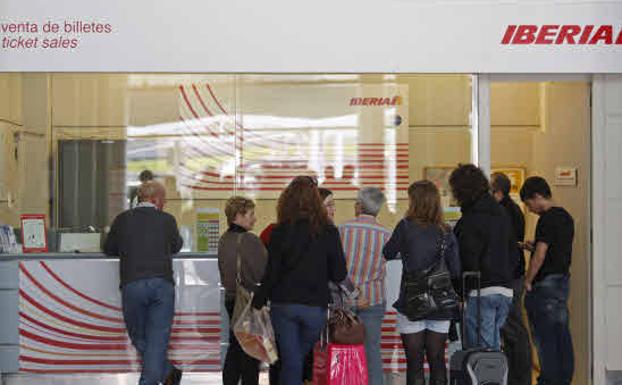 Varios pasajeros esperan en el mostrador de una compañía aérea en un aeropuerto de Aena.