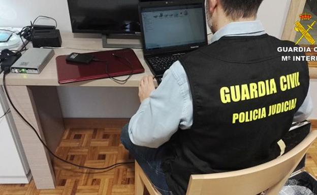 Un agente de la Guardia Civil analiza uno de los ordenadores incautados. 